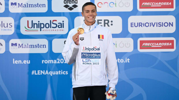Romanian swimmer David Popovici poses with a gold medal after breaking the 100-meter freestyle record.